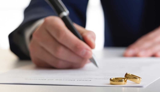 Lawyer preparing divorce paperwork with two wedding rings nearby